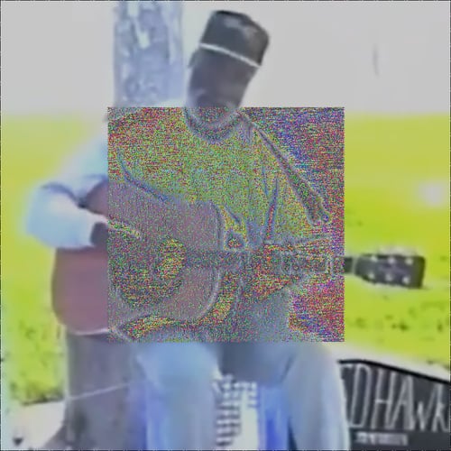 A medium VHS-recorded shot of Ted Hawkins sitting on a makeshift stool on the Venice Beach boardwalk, longsleeve shirt, ballcap, acoustic guitar in hand. The cropped letters 'Ed Hawk' can be seen in tall handwriting on a open guitar case on the right side of the image on the ground. The image is sunlit high contrast with a lot of white and green. In the center is a square covering half the image with intense red, blue, yellow, and green noise.